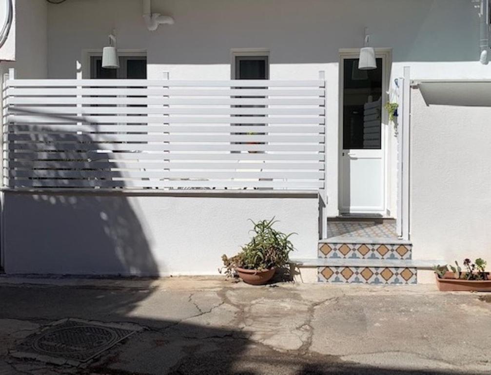 een wit huis met een hek en potplanten bij Casa Nica in Mondello
