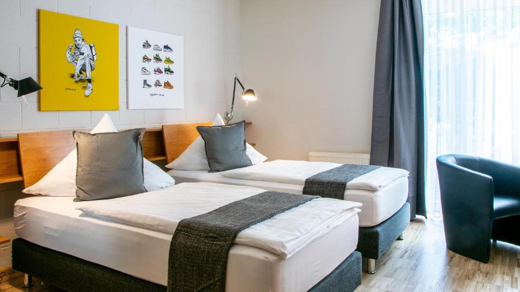 ein Hotelzimmer mit 2 Betten und einem Stuhl in der Unterkunft IMPULSIV Hotel & Sportresort in Lörrach