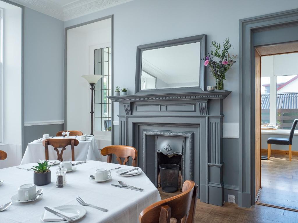 uma sala de jantar com uma mesa e um espelho sobre uma lareira em Cairngorm Guest House em Aviemore