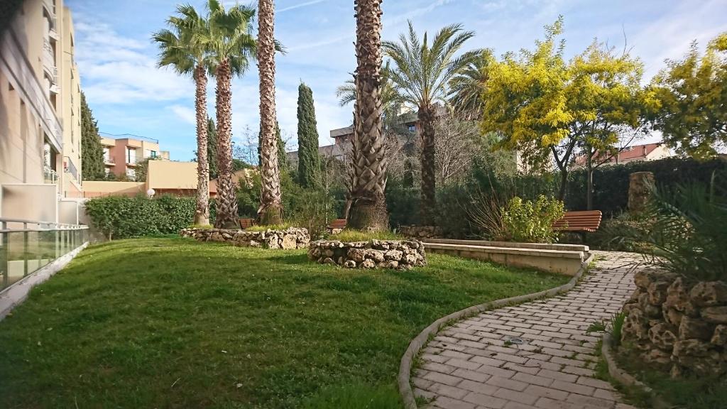 un jardin avec des palmiers et une passerelle en briques dans l'établissement Nicolas 2, à Cannes