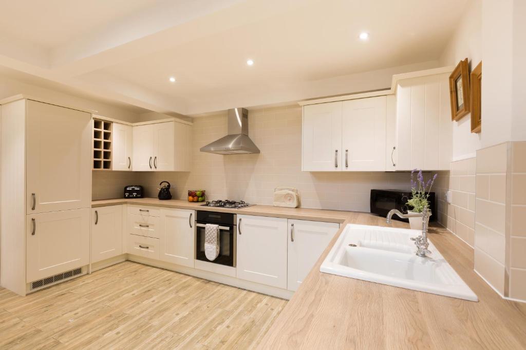 a kitchen with white cabinets and a sink at Warkworth House Hotel in Warkworth