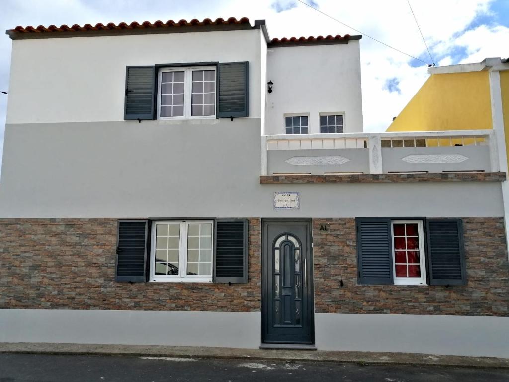 une maison blanche avec des fenêtres à volets noirs et une porte dans l'établissement Casa Pôr do Sol, à Ginetes