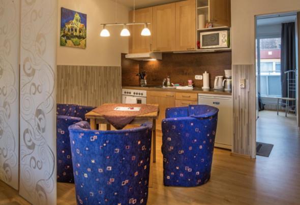 a kitchen with a wooden table and blue stools at H&H Apartments im Herzen der Stadt teilweise mit Balkon ruhig zentral modern mit Küche in Greifswald