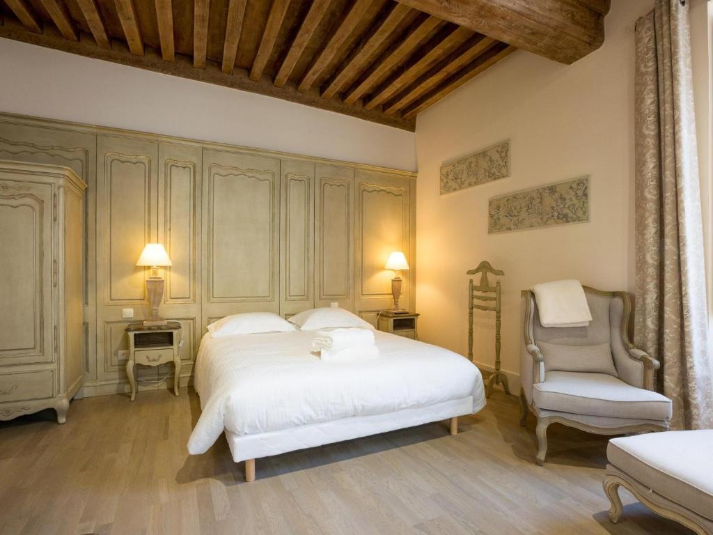 a bedroom with a large white bed and a chair at Le Cara Sehiah 1D in Beaune
