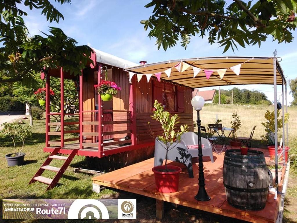 a red caravan with awning and a table in a yard at La roulotte d'Elicie Proche du Parc le Pal in Saint-Agnan-sur-Loire