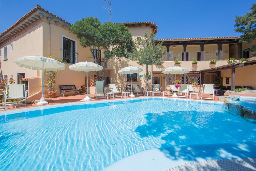 una grande piscina con sedie e ombrelloni di Hotel Colonna San Marco a Porto Rotondo