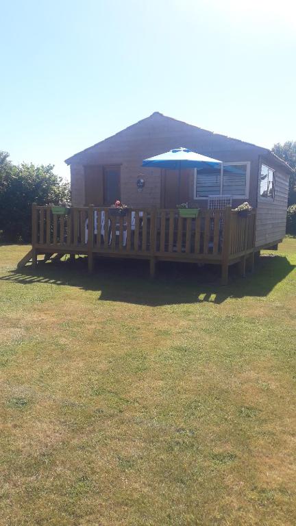 a small house with a porch and an umbrella at Le Chal Adret in Cardonville