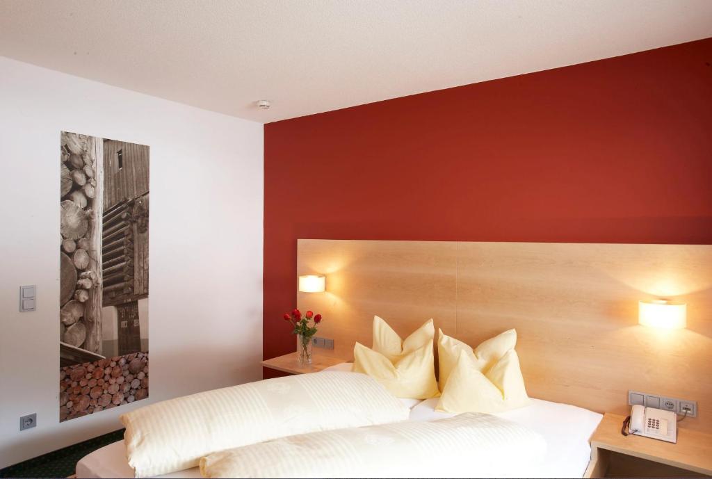 a bedroom with a white bed and a red wall at Hotel Sonnblick in Gaschurn