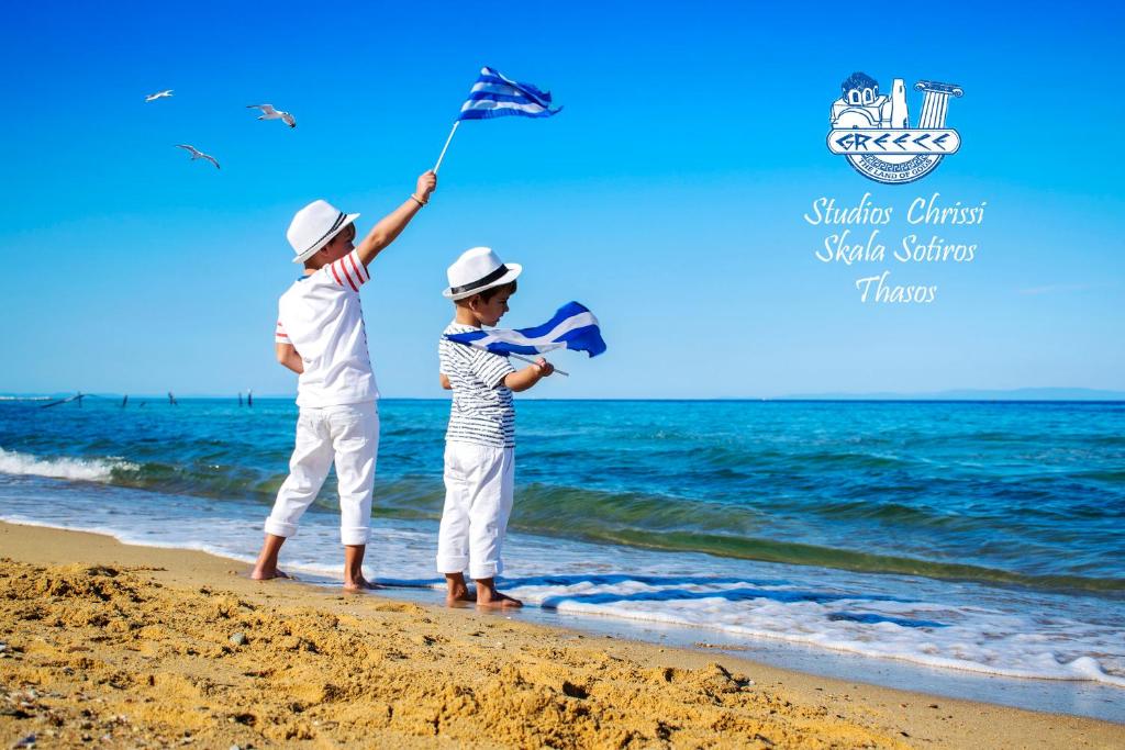 two children are flying a kite on the beach at Studios Chrissi in Skala Sotiros