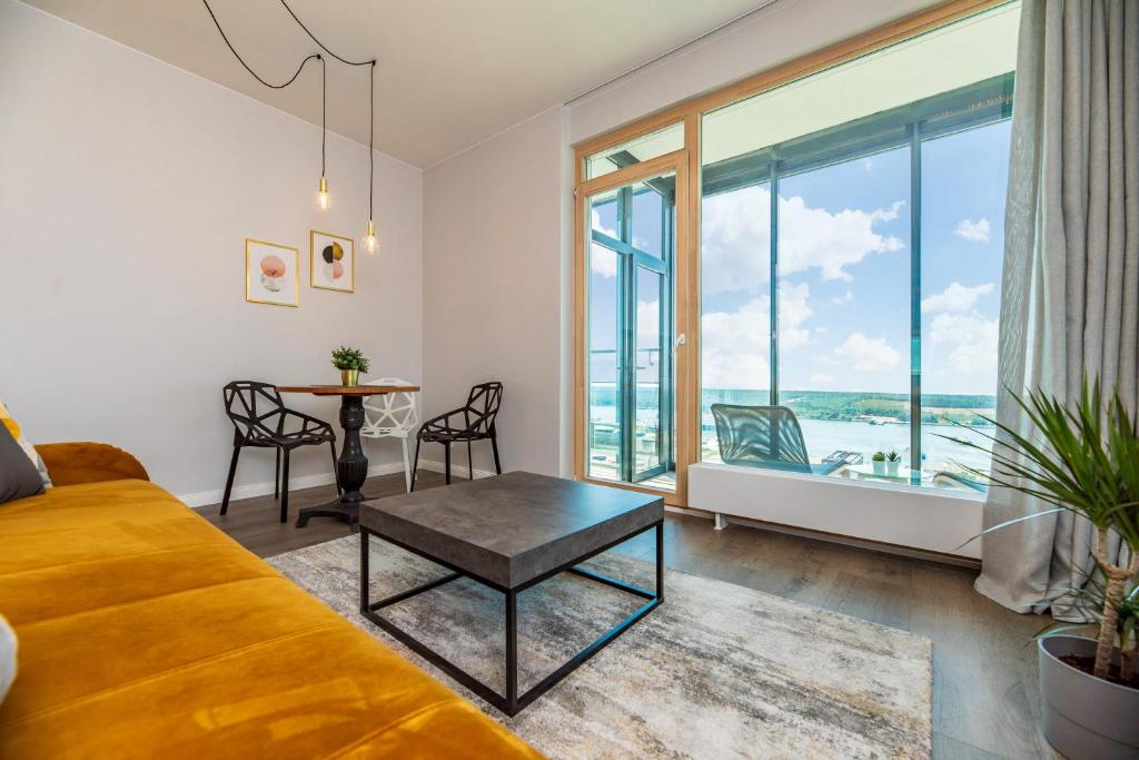 een woonkamer met een bank en een tafel bij Modern spacious studio w/ Sea Views in Klaipėda