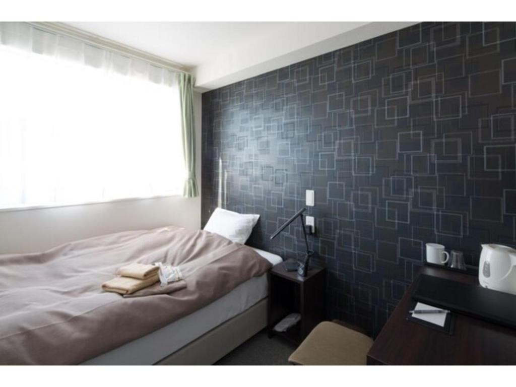 1 dormitorio con 1 cama con pared de azulejos azules en C-style inn SOMA 34 - Vacation STAY 87845, en Soma