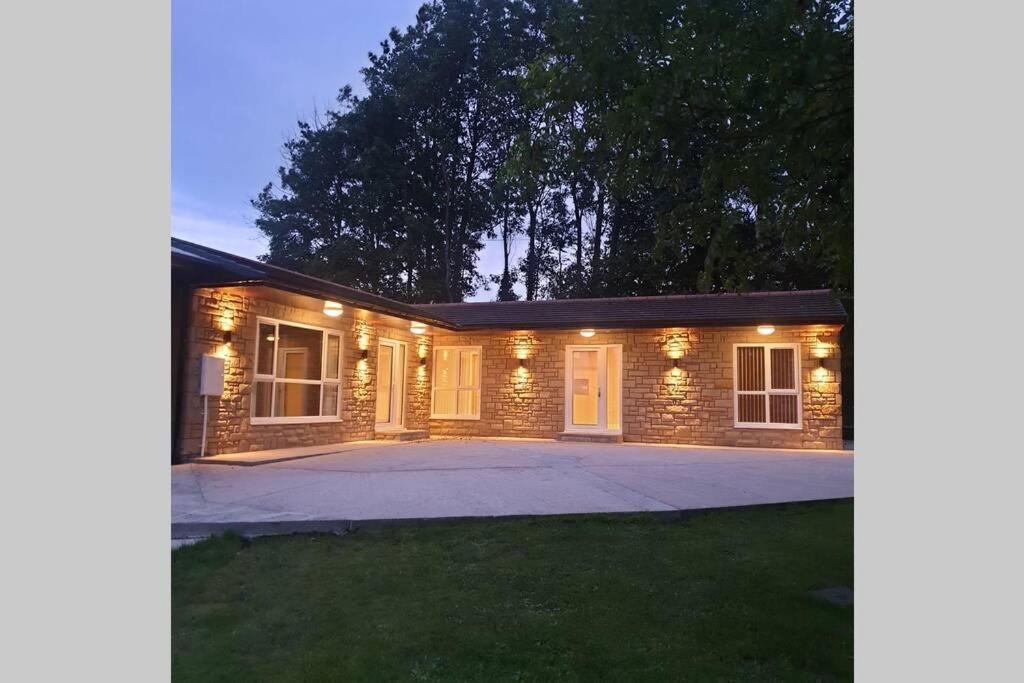 a brick house with lights on a driveway at Luxury five star cottage one 