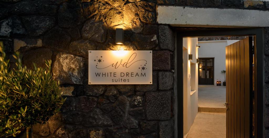 a sign for a white dream suites on a stone wall at White Dream Suites in Fira