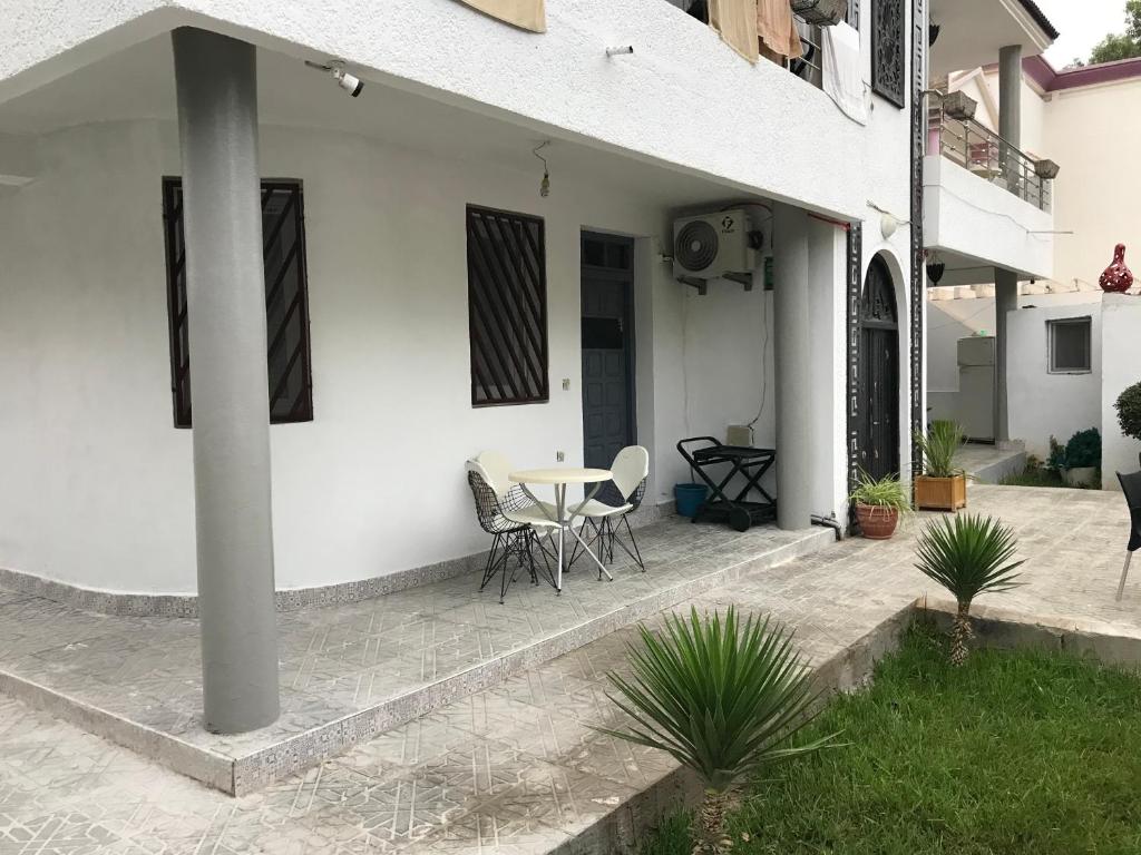 Cette maison blanche dispose d'une terrasse avec une table et des chaises. dans l'établissement Too Many Suites, à Saïdia