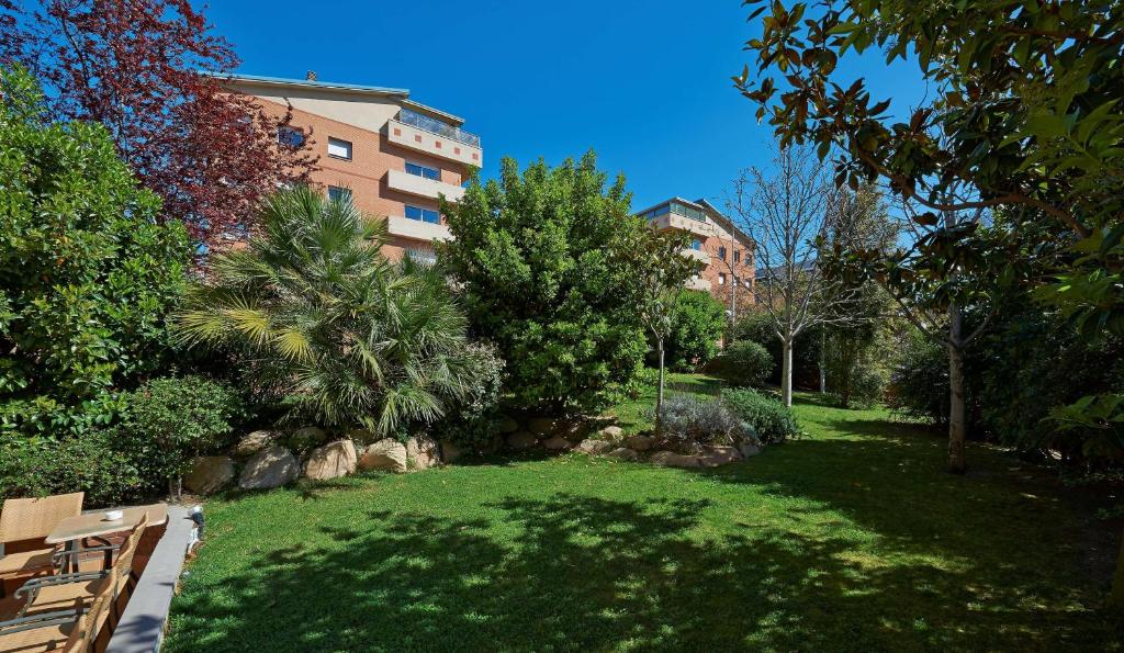 un parque con bancos y árboles y un edificio en Sercotel Porta Barcelona, en Sant Just Desvern
