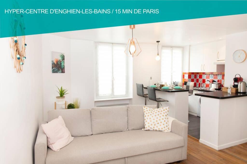 a living room with a couch and a kitchen at Cœur de ville Enghien les Bains - 2 pièces Lumineux et Chaleureux - 15 min de Paris in Enghien-les-Bains