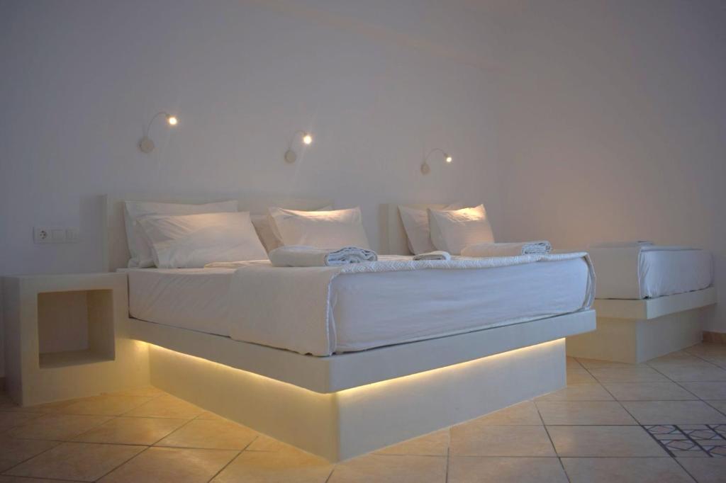 a bedroom with a large white bed with lights on it at Virginia Studios in Tinos