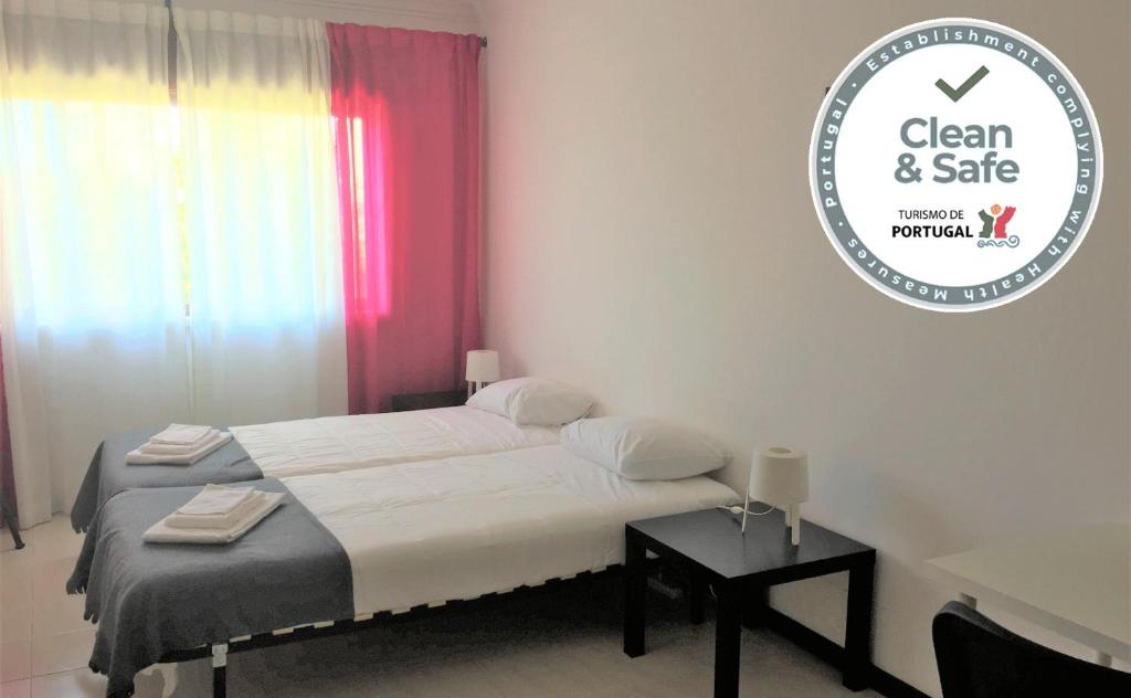 a bedroom with a bed and a table and a sign at APARTAMENTO LISBOA - REBOLEIRA in Amadora