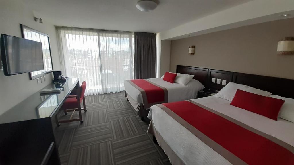 a hotel room with two beds and a flat screen tv at Ramada Plaza by Wyndham Leon in León