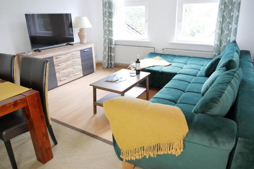 uma sala de estar com um sofá verde e uma televisão em Ferienwohnung Werenberg Goslar em Goslar