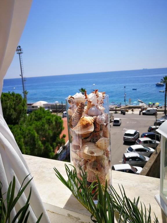 a glass vase filled with seashells on a table next to the beach at B&B Il Mare degli Dei in Letojanni