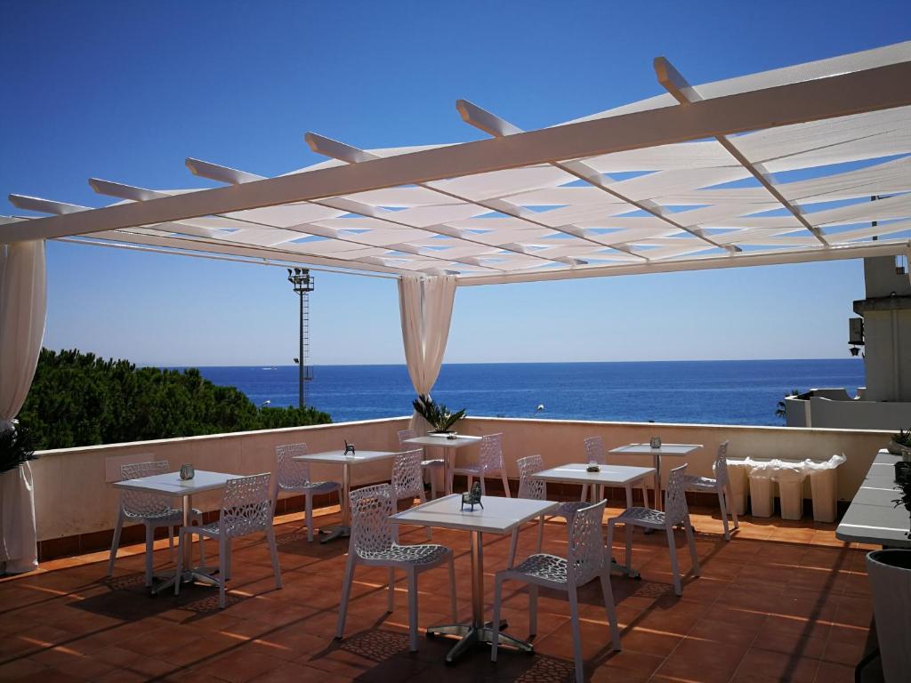a patio with tables and chairs and the ocean at B&B Il Mare degli Dei in Letojanni