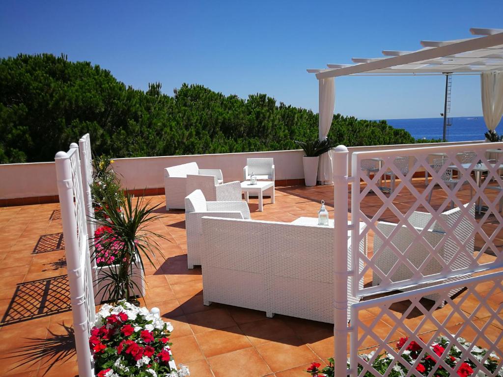 a patio with white chairs and an umbrella at B&B Il Mare degli Dei in Letojanni