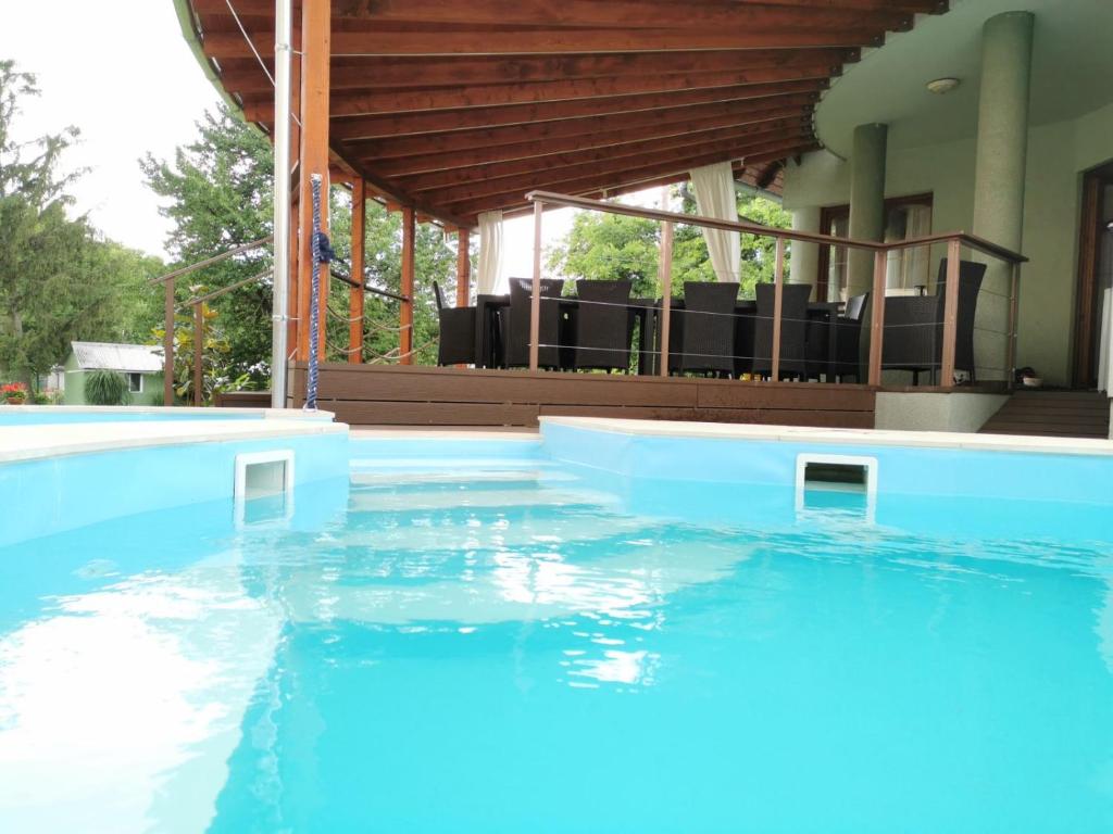 a large swimming pool with blue water in front of a house at House4U in Balatonszemes