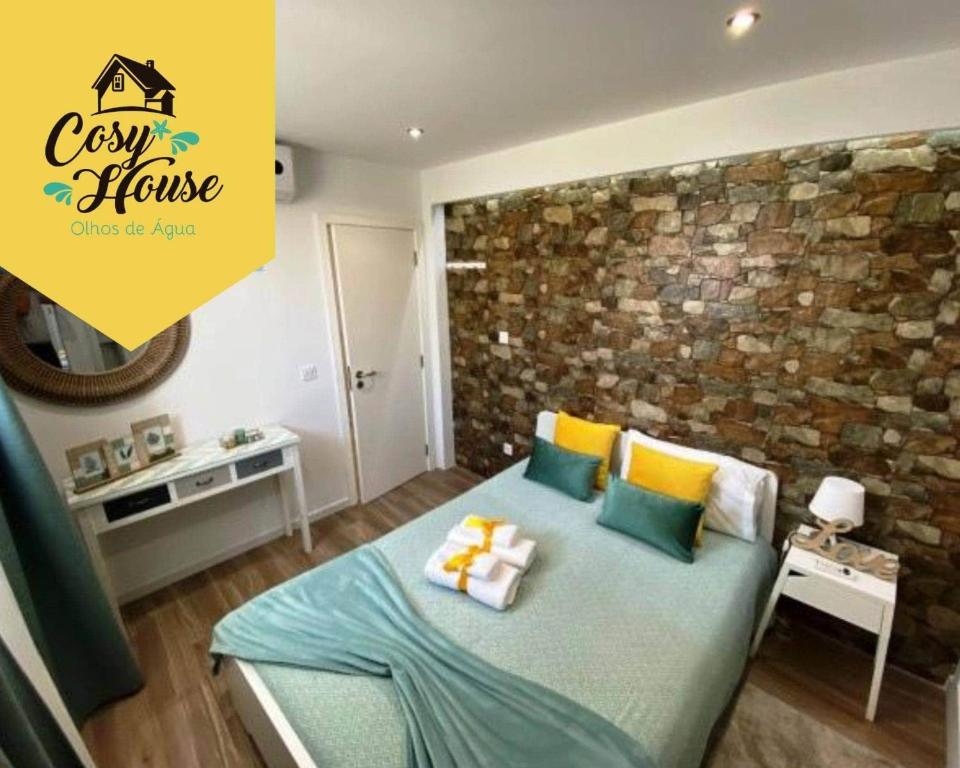 um quarto com uma cama com almofadas e uma parede de tijolos em Cosy House em Albufeira