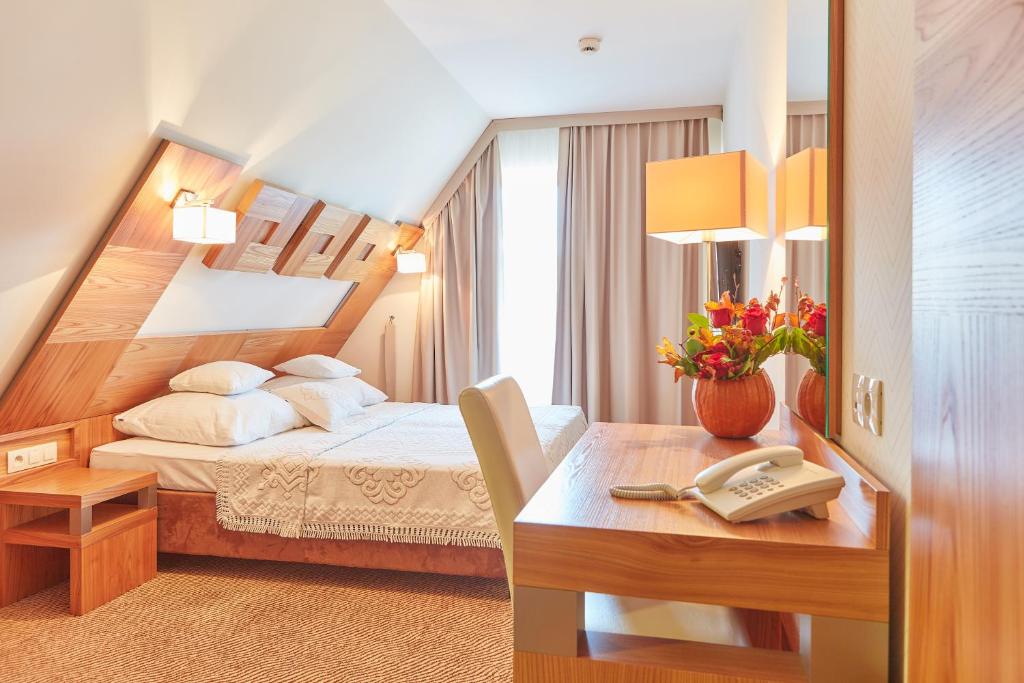 a bedroom with a bed and a desk with a phone at Hotel Zbójnicówka in Bukowina Tatrzańska