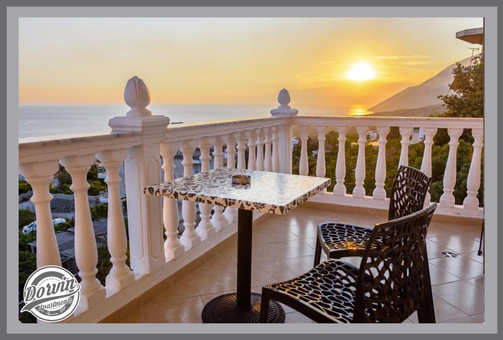 a table and chairs on a balcony with the sunset at Dorvin Apartments in Dhërmi