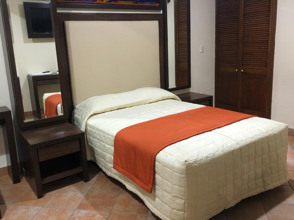 a bedroom with a bed with an orange blanket at Hostal Nordés in Oaxaca City
