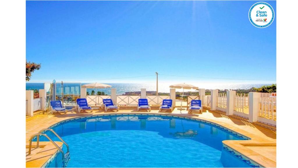 una piscina con sedie a sdraio e vista sull'oceano di Villa Albuar ad Albufeira