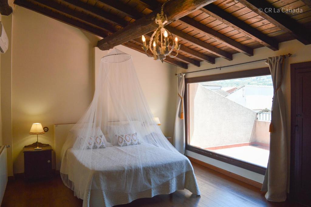 Casa Rural La Cañada في الديانويفا ديل كامينو: غرفة نوم بسرير وثريا ونافذة