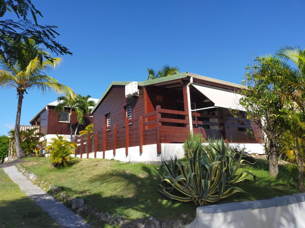 une maison en bois avec des palmiers devant elle dans l'établissement Ti Village Creole, à Sainte-Anne