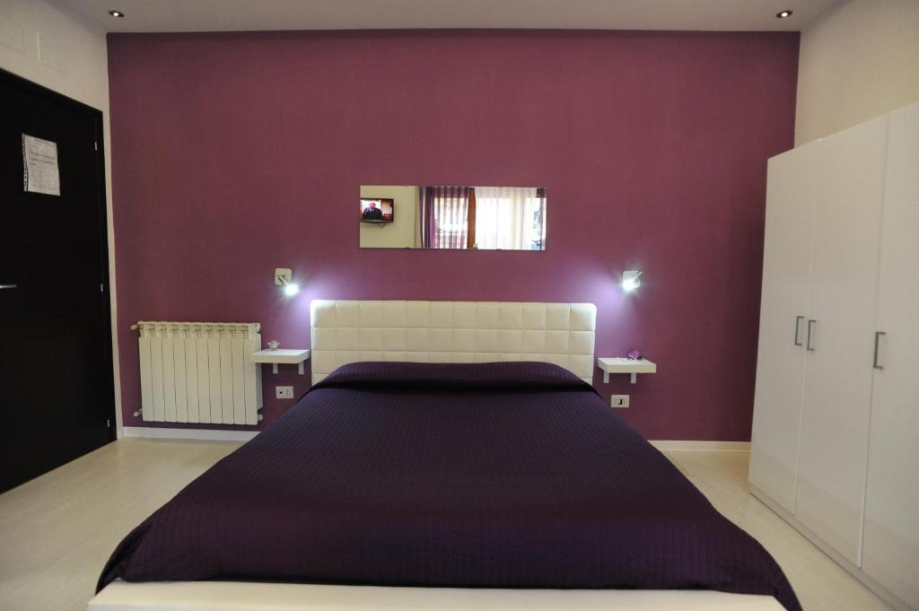 1 dormitorio con 1 cama grande y paredes moradas en Magic Rainbow, en Segni