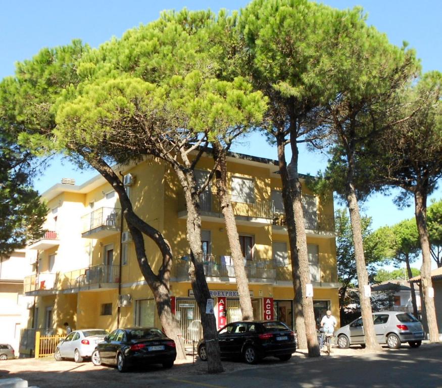 a group of trees in front of a building at Fides Apartment in Rosolina Mare