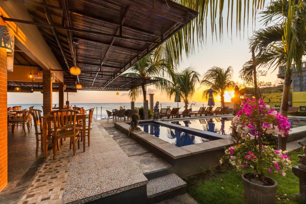 um resort com piscina, mesas e cadeiras em Amed Beach Resort em Amed
