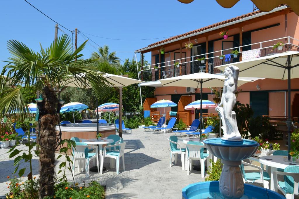 a resort with tables and chairs and a fountain at Billy's Rooms in Moraitika