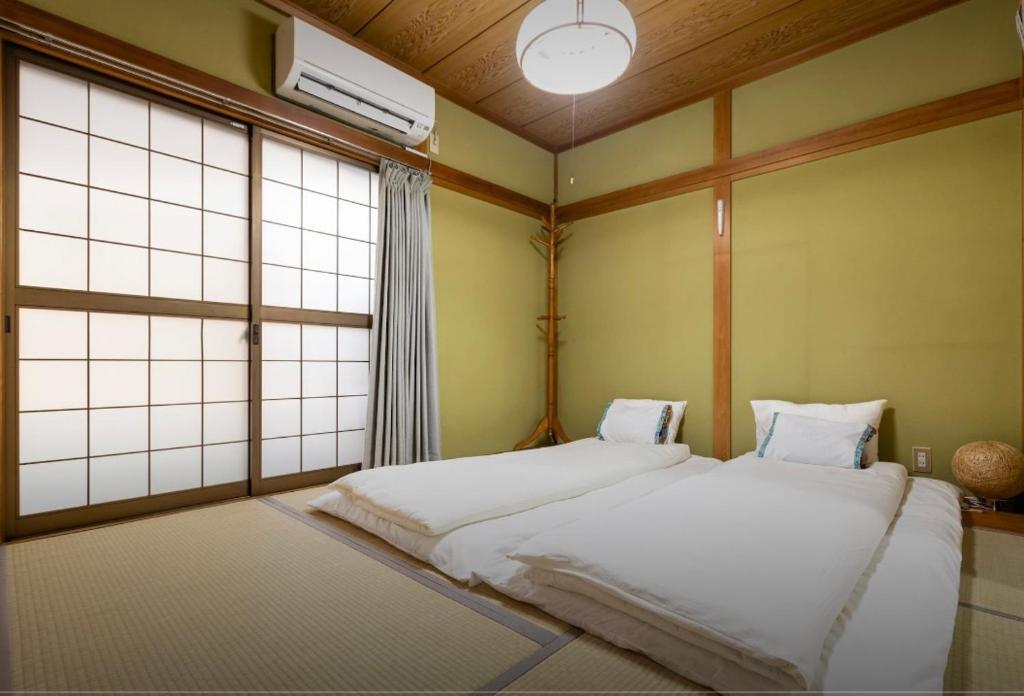 a bedroom with two beds and a window at 10mins train to Namba, 4 mins walk to stn, 2 floors japanese style , 2-8 people in Osaka