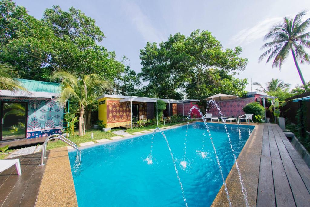 a swimming pool with a wooden deck next to a house at Tisha Langkawi Wellness Resort in Pantai Cenang