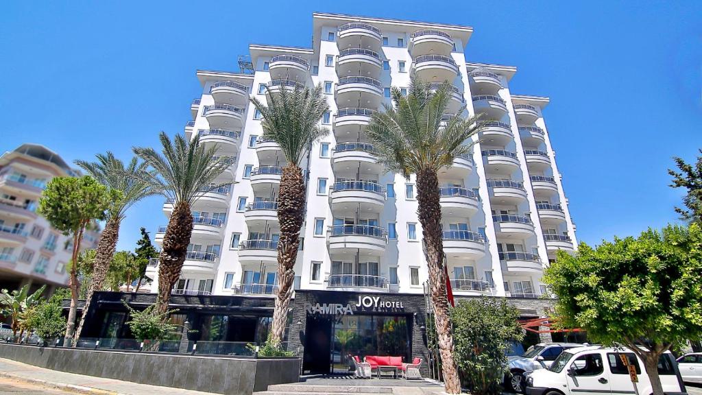 een wit gebouw met palmbomen ervoor bij Ramira Joy Hotel in Alanya