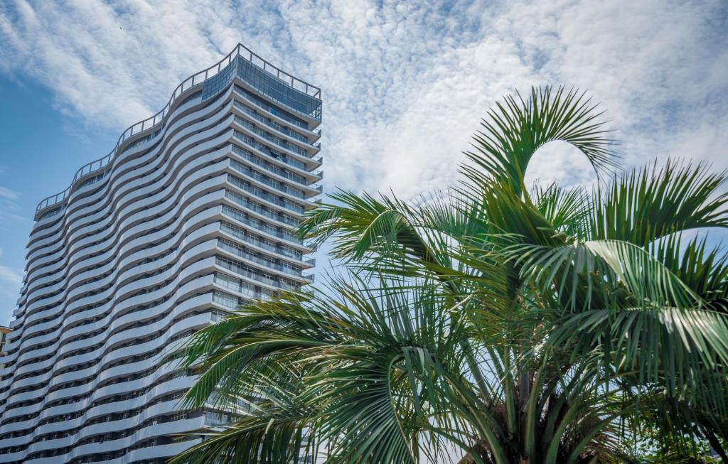een hoog gebouw met palmbomen ervoor bij Orbi Residence Hotel Official in Batoemi