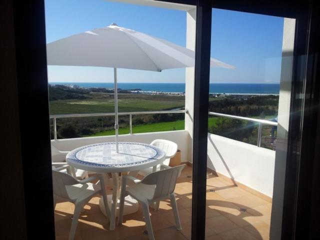 a table and chairs with an umbrella on a balcony at Les Jardins d'Asilah in Asilah