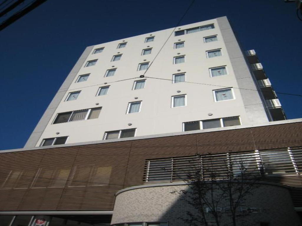 un grand bâtiment blanc devant un bâtiment dans l'établissement Kumagaya Royal Hotel Suzuki, à Kumagaya