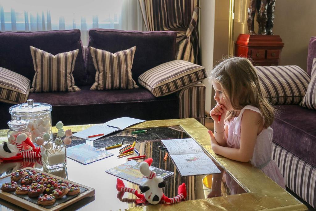 a little girl sitting at a table in a living room at Hôtel de la Cigogne in Geneva