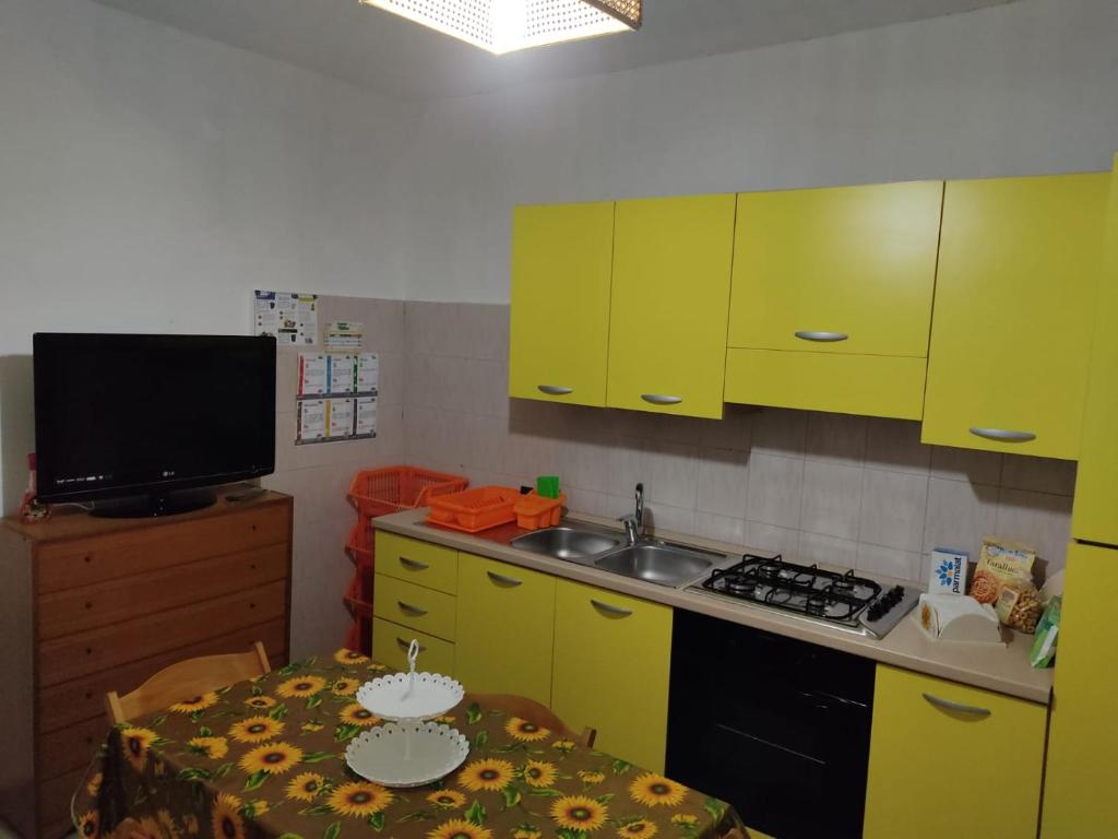 a kitchen with yellow cabinets and a table and a sink at Casa Vacanza Villa Teresa - Appartamento Girasole in Torre Lapillo