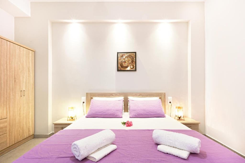 a bedroom with a large bed with purple sheets and pillows at Stenaki in Skiathos Town