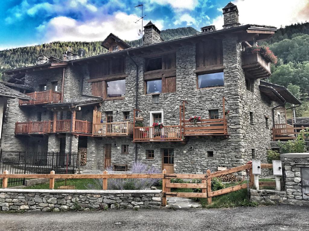 un gran edificio de piedra con balcones de madera. en Bilocale pietra e legno immerso nella natura en Morgex