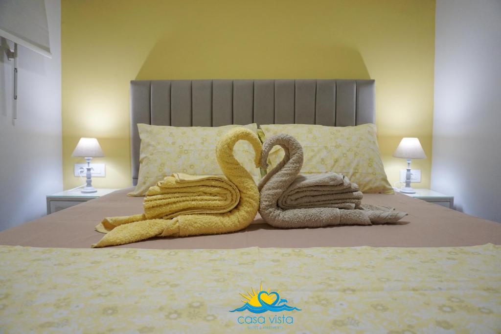 2 cygnes de serviettes assises au-dessus d'un lit dans l'établissement Casa Vista Spring, à Karpathos